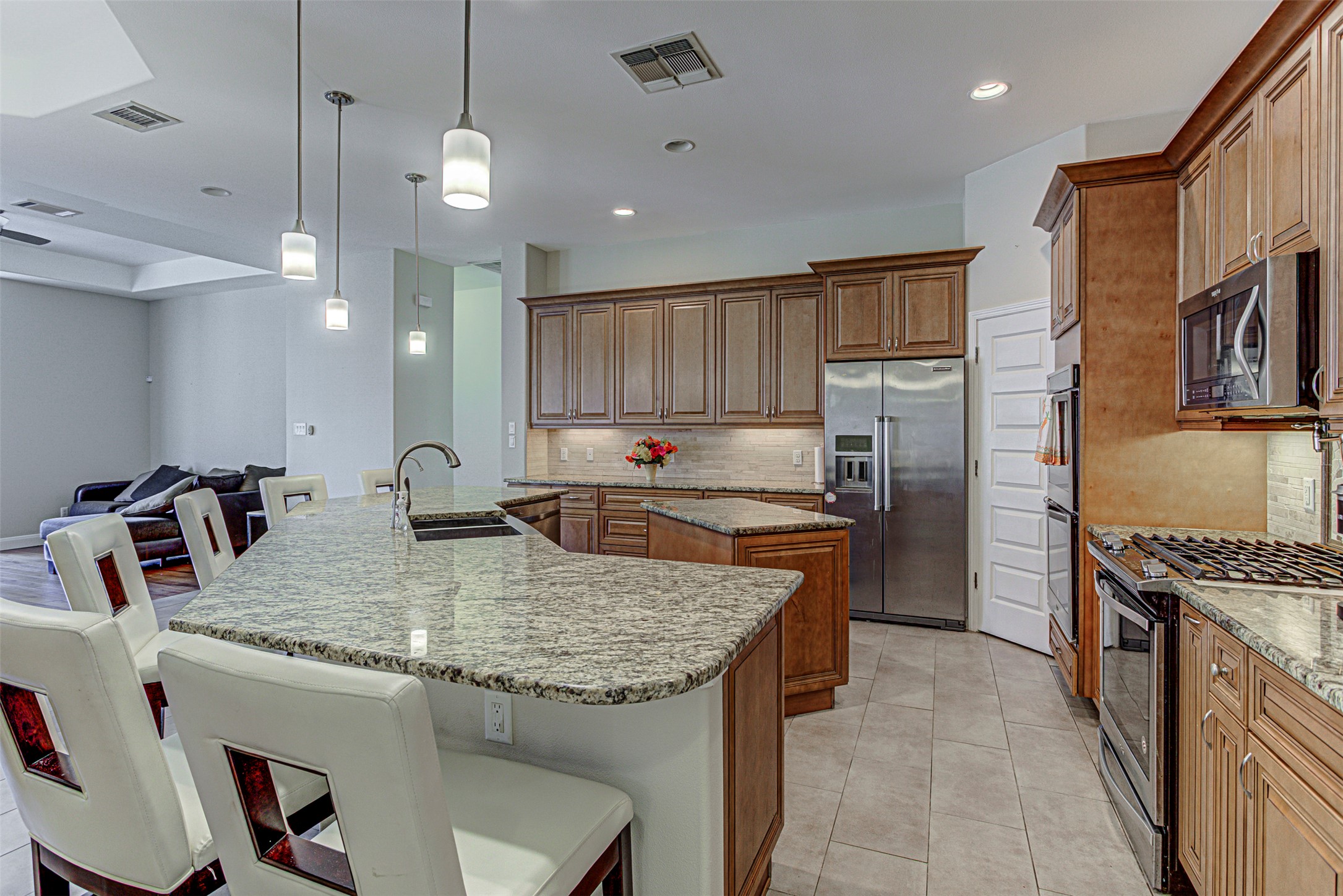 105 Arbors Circle Elgin, TX 78621 - Photo 12 of 40 Kitchen featuring stainless steel appliances, light stone countertops, wood finish cabinets, and a kitchen bar