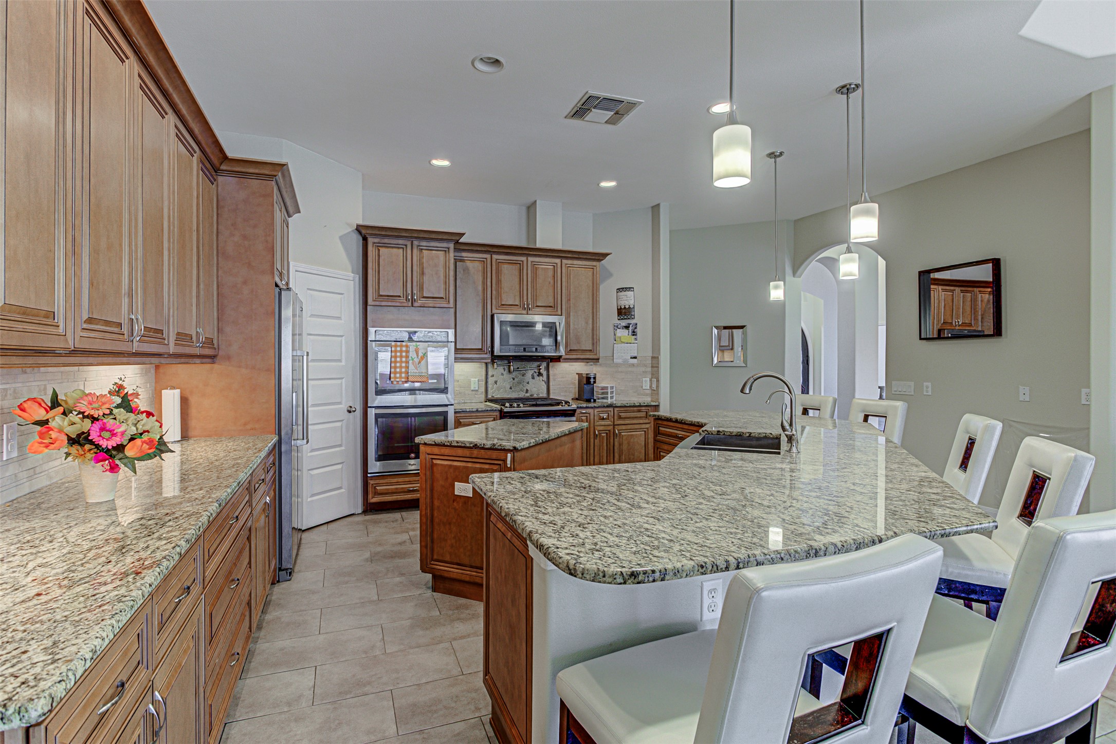 105 Arbors Circle Elgin, TX 78621 - Photo 14 of 40 Kitchen featuring wood finish cabinetry, a kitchen breakfast bar, backsplash, stainless steel appliances, and light stone counters
