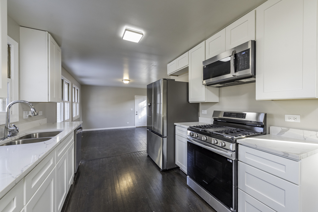 821 12th Street North Chicago, IL 60064 - Photo 8 of 25 a kitchen with stainless steel appliances a sink a stove a microwave and cabinets