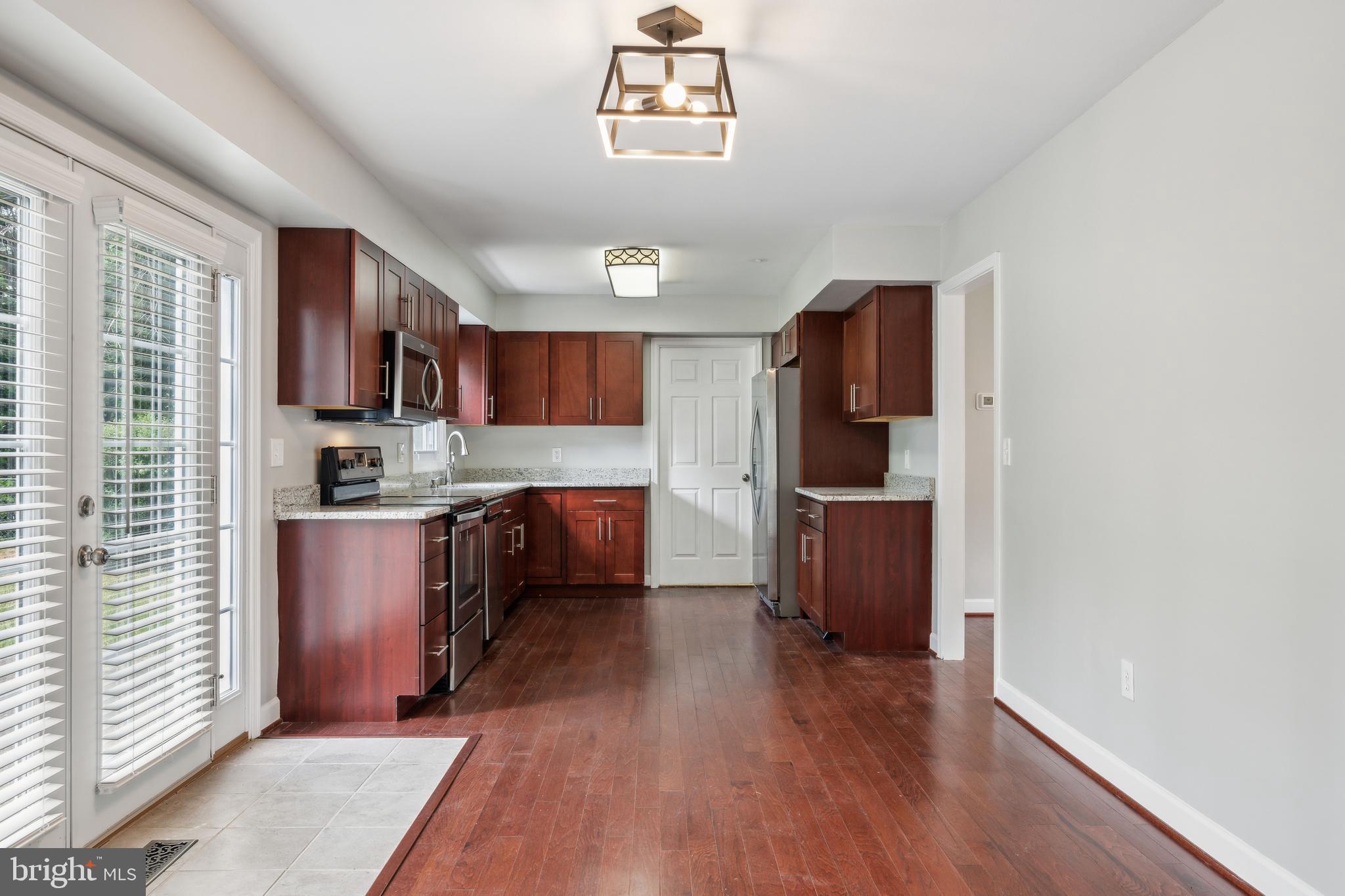 12430 Shadow Lane Bowie, MD 20715 - Photo 6 of 24 a kitchen with stainless steel appliances granite countertop a refrigerator a sink dishwasher a stove with wooden cabinets and floor
