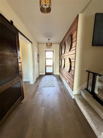 a view of a hallway with wooden floor and stairs