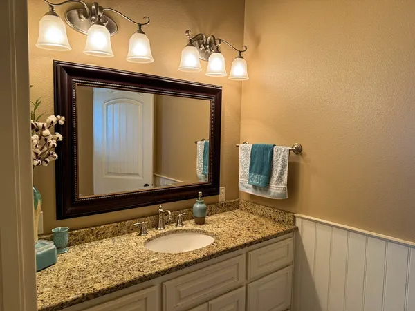 a bathroom with a granite countertop sink and a mirror