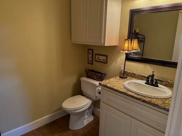 a bathroom with a granite countertop toilet sink and mirror
