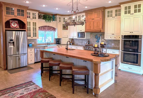 a kitchen with stainless steel appliances a stove a sink a refrigerator and chairs