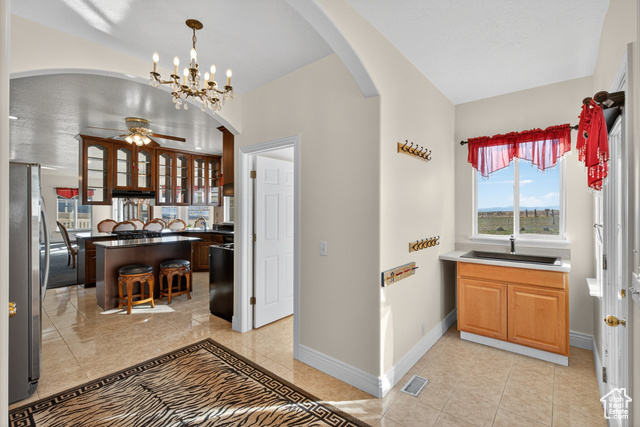 4768 East Hickman Canyon Road Stockton, UT 84071 - Photo 5 of 85 Front entry way through mud room into kitchen, a chandelier, freestanding refrigerator, see through cabinets, and hanging light fixtures.