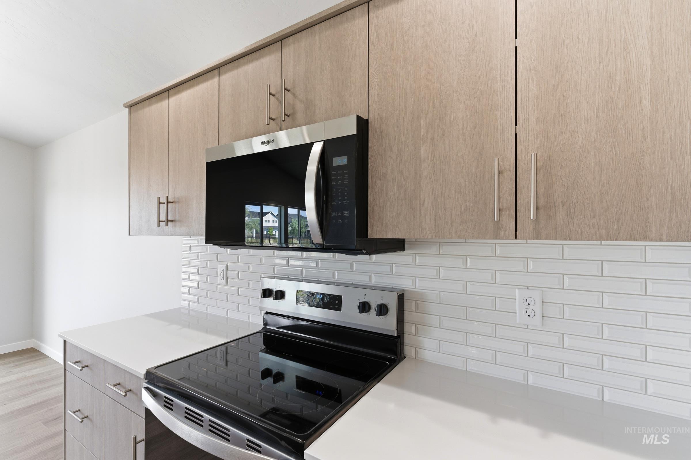 1059 West Jasper Street Meridian, ID 83642 - Photo 4 of 23 Contemporary kitchen featuring a stainless steel electric range, built-in microwave, white subway tile backsplash, light wood-finish cabinetry, and white countertops
