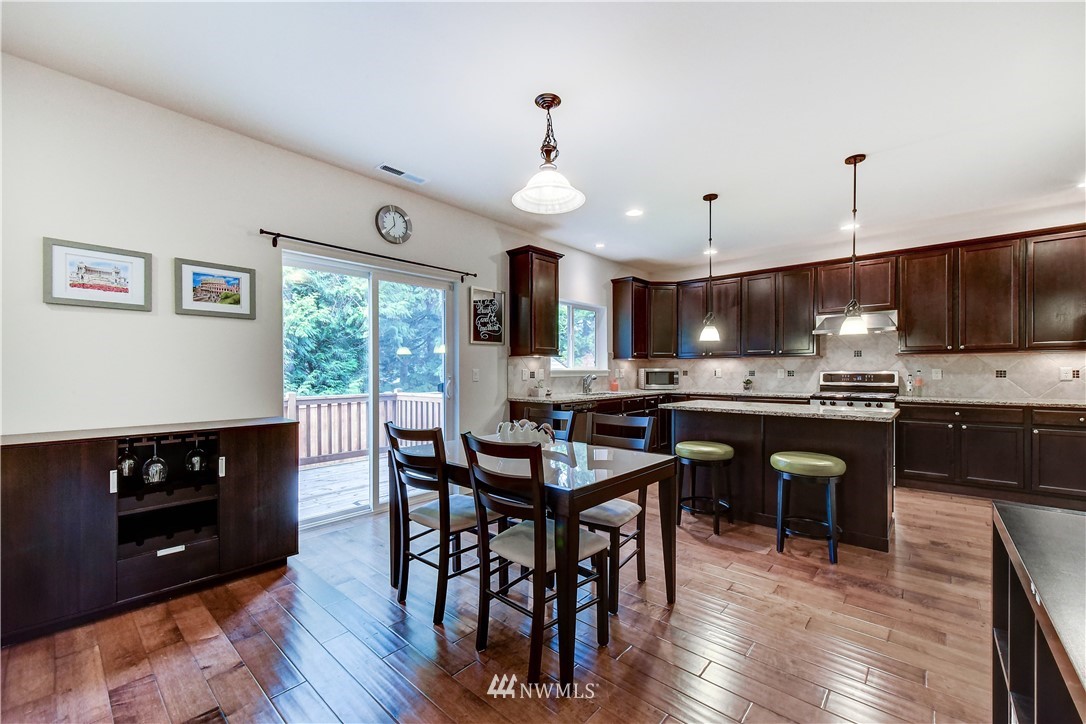 22330 35th Drive Southeast Bothell, WA 98021 - Photo 8 of 25 a kitchen with stainless steel appliances granite countertop a stove a refrigerator a kitchen island a dining table and chairs with wooden floor