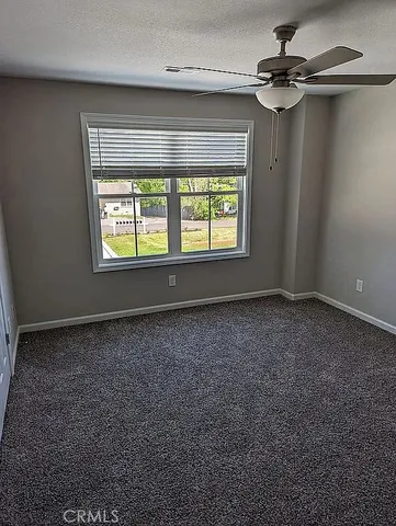 en empty room with windows and chandelier fan