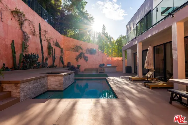 a view of swimming pool with lawn chairs and plants