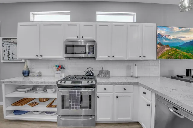 a kitchen with stainless steel appliances granite countertop a refrigerator a stove a sink and a microwave