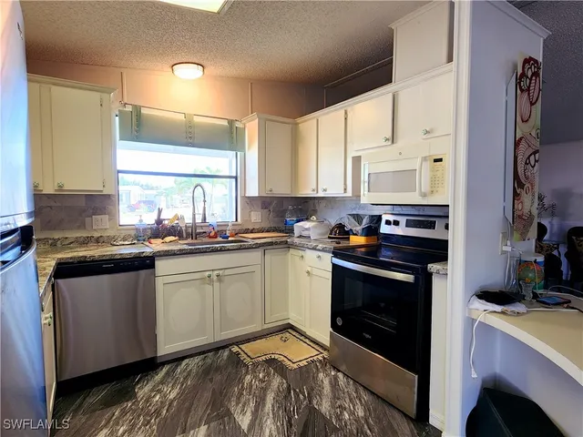 a kitchen with granite countertop cabinets stainless steel appliances and a sink