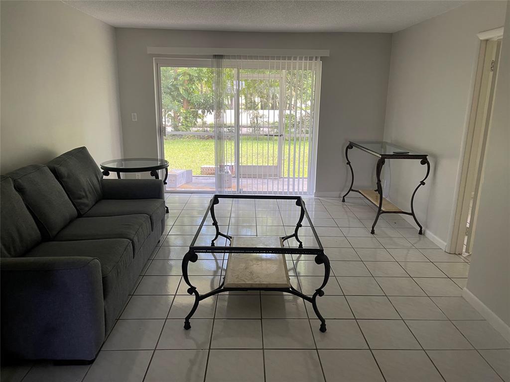 8405 Northwest 61st Street, Unit D109 Tamarac, FL 33321 - Photo 3 of 25 a living room with furniture and a floor to ceiling window