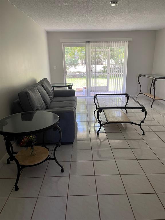 8405 Northwest 61st Street, Unit D109 Tamarac, FL 33321 - Photo 4 of 25 a living room with furniture and a floor to ceiling window