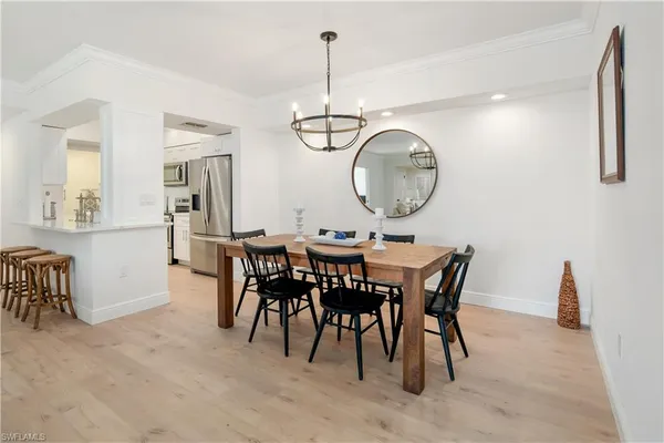 a dining room with wooden floor a chandelier a wooden table and chairs