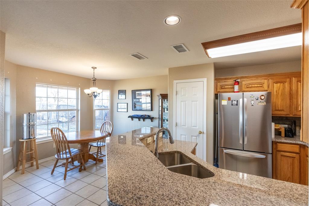 2166 County Road 131 Tuscola, TX 79562 - Photo 11 of 40 a kitchen with granite countertop a refrigerator a stove a dining table and chairs with wooden floor