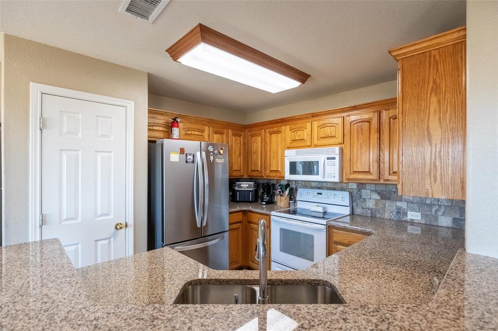 2166 County Road 131 Tuscola, TX 79562 - Photo 16 of 40 a kitchen with granite countertop a refrigerator and a sink