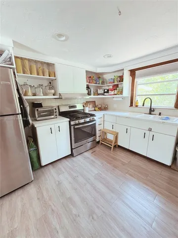 a kitchen with granite countertop a sink cabinets and wooden floor