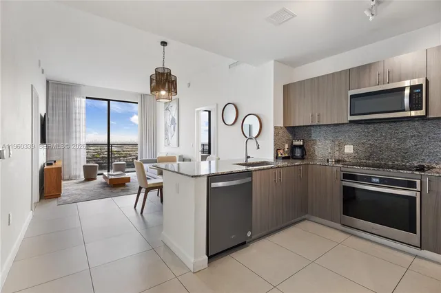 a open kitchen with stainless steel appliances granite countertop a stove top oven a sink dishwasher and a microwave oven with white cabinets