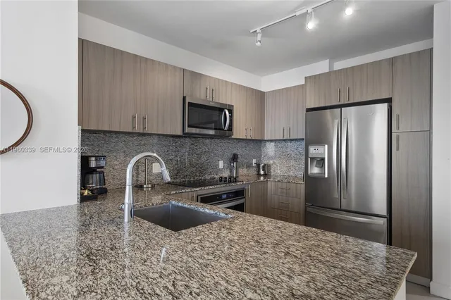 a kitchen with stainless steel appliances granite countertop a refrigerator sink and stove