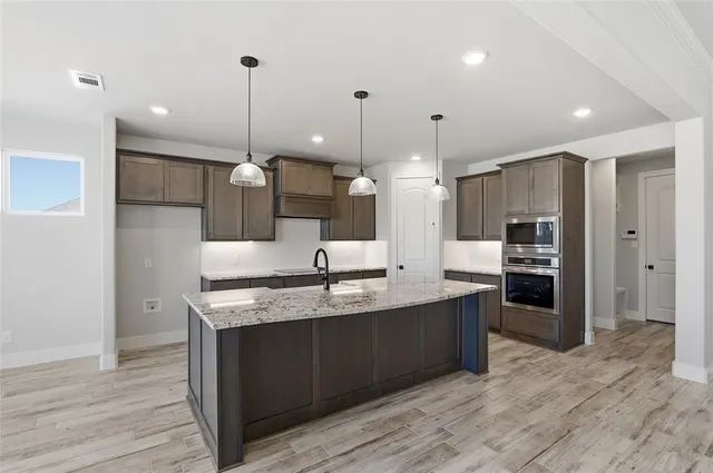 a large kitchen with stainless steel appliances kitchen island granite countertop a sink a counter space and cabinets