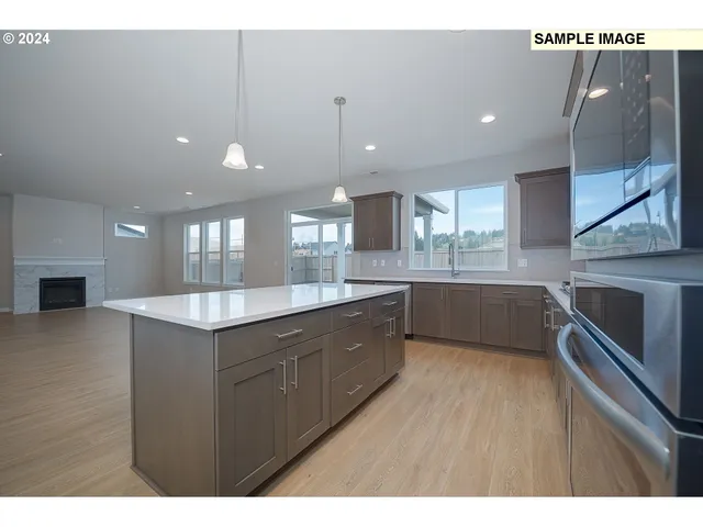 a large kitchen with a counter space a sink stainless steel appliances and cabinets