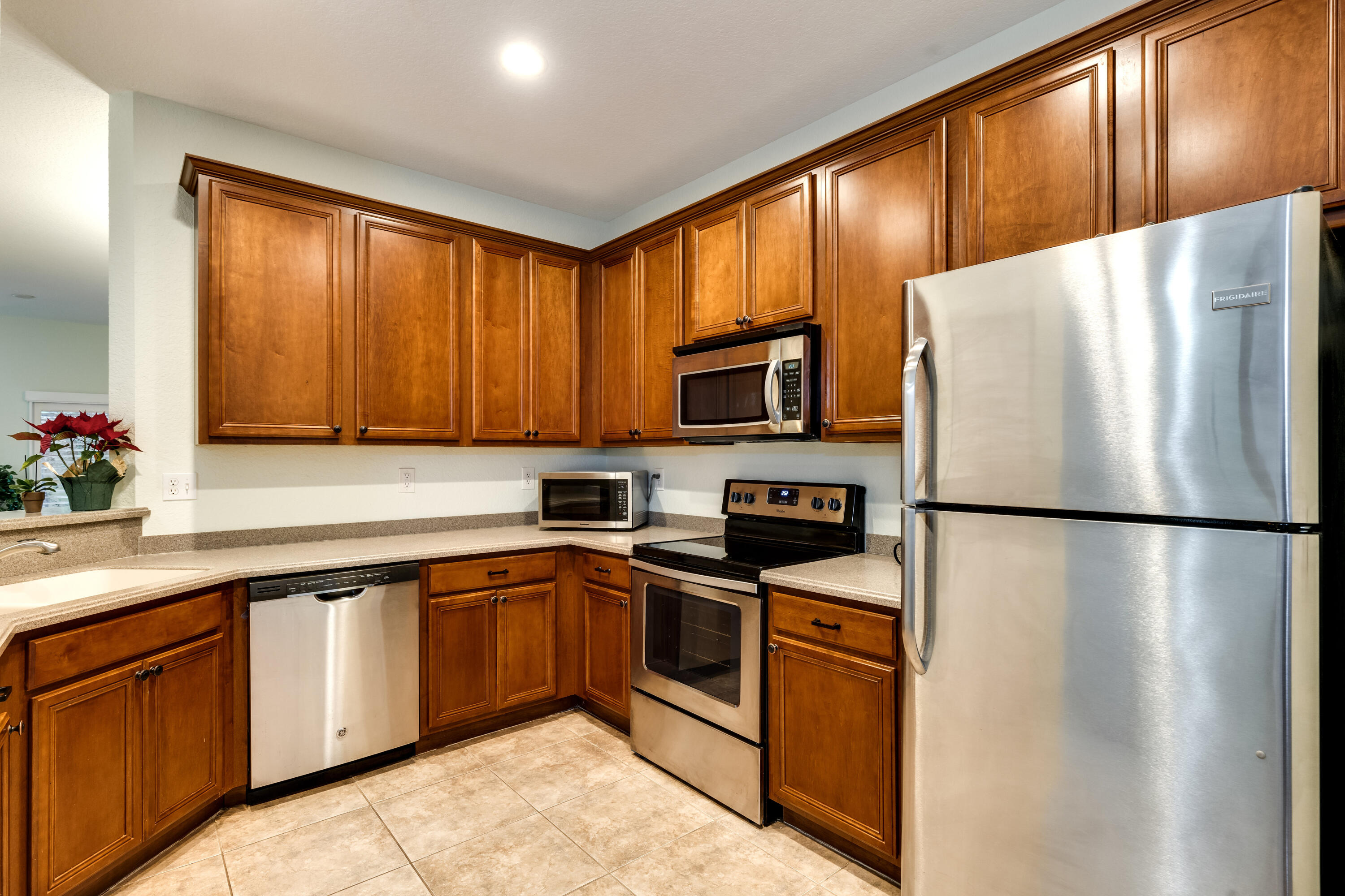 156 Village Boulevard, Unit E Tequesta, FL 33469 - Photo 11 of 36 a white refrigerator freezer sitting inside of a kitchen with stainless steel appliances granite countertop wooden cabinets washer and a sink