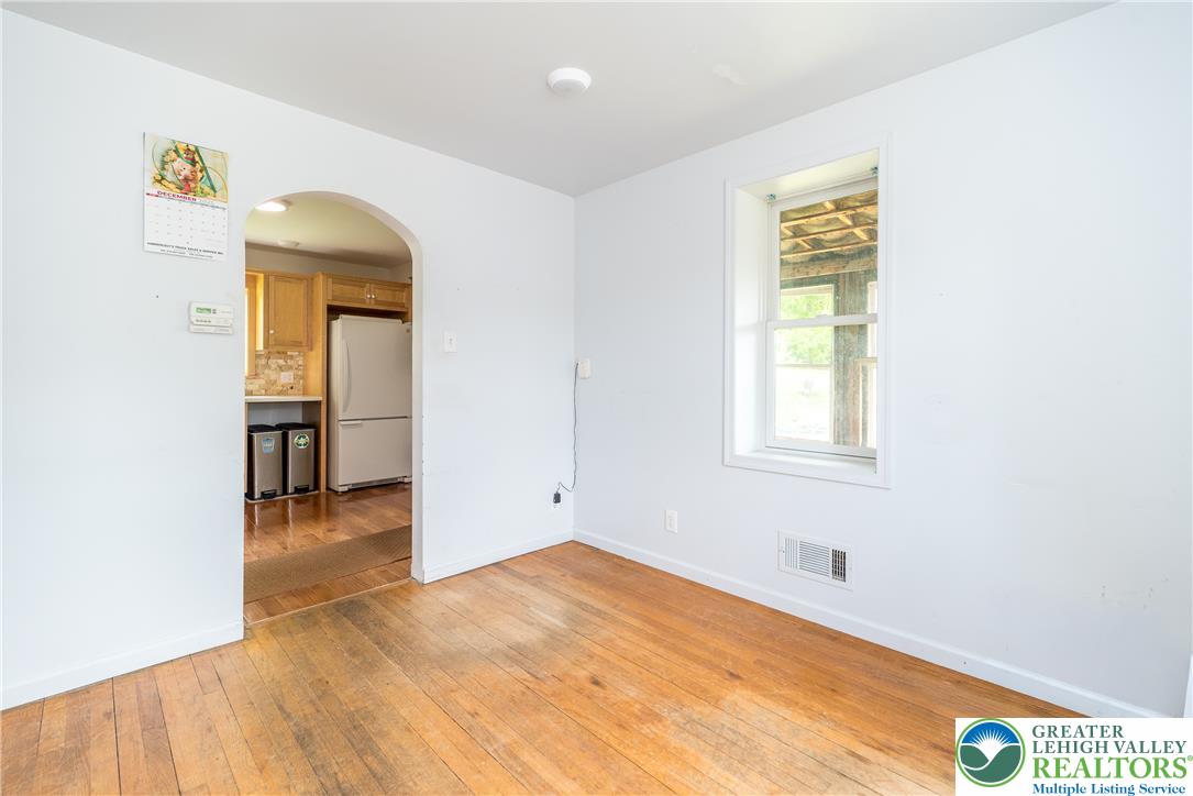 1815 Leithsville Road Hellertown, PA 18055 - Photo 10 of 38 A well-lit room with warm hardwood flooring and an inviting arched doorway leading to the kitchen.