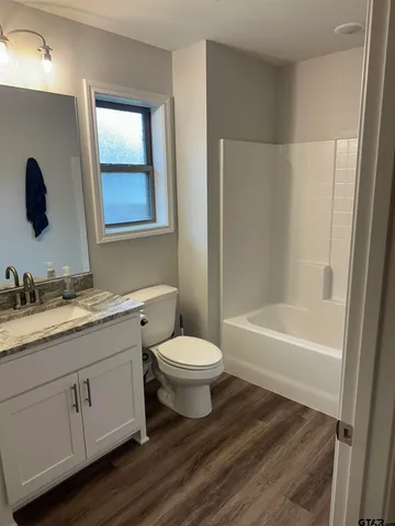 a bathroom with a granite countertop sink toilet a large mirror a bathtub and shower