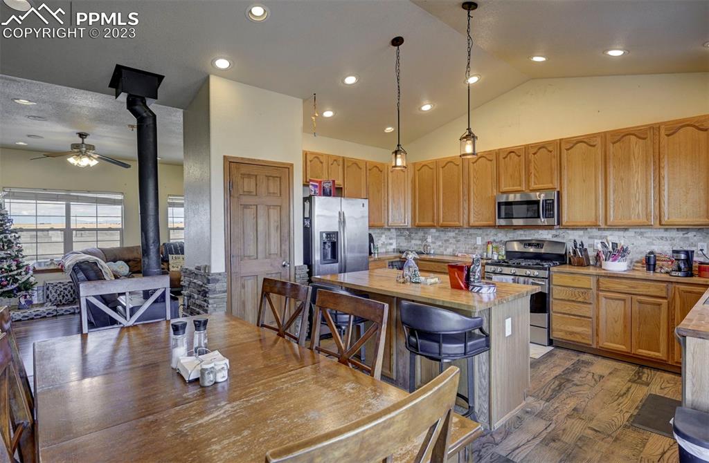 31790 Sanborn Road Yoder, CO 80864 - Photo 12 of 50 a kitchen with stainless steel appliances granite countertop a stove top oven a sink dishwasher a dining table and chairs with wooden floor