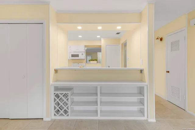 a view of a hallway to a room with wooden floor and cabinet