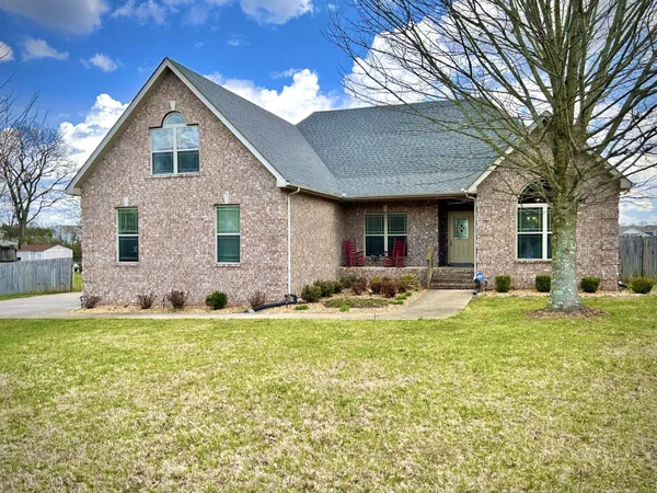 a front view of house with yard and trees in the background