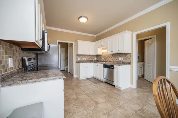 a kitchen with granite countertop white cabinets and stainless steel appliances