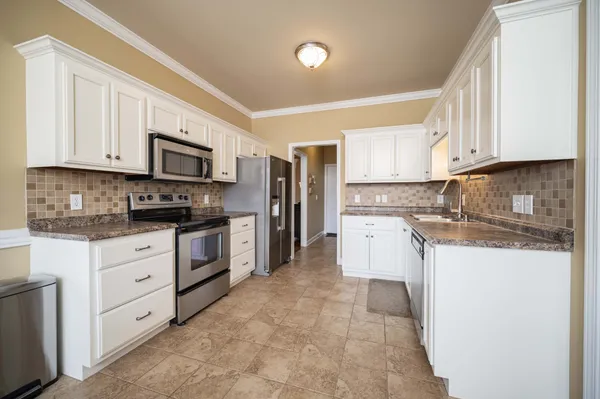 a kitchen with stainless steel appliances granite countertop a stove top oven a sink dishwasher and a refrigerator