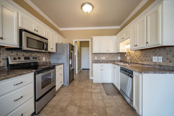a large kitchen with stainless steel appliances granite countertop a stove granite counter tops and a view of living room