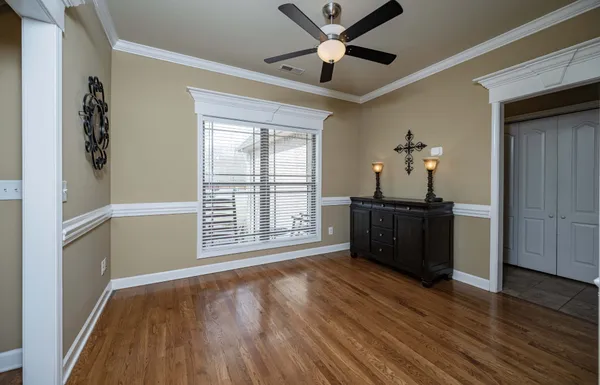 a view of empty room with wooden floor and fan