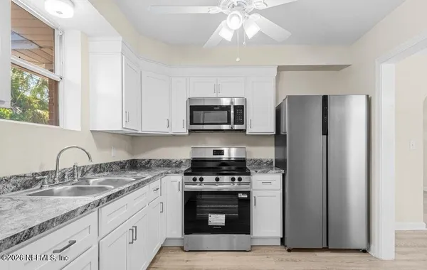 a kitchen with granite countertop a refrigerator stove and microwave