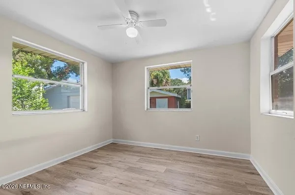 a view of empty room with wooden floor and fan