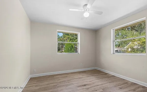 an empty room with wooden floor and windows
