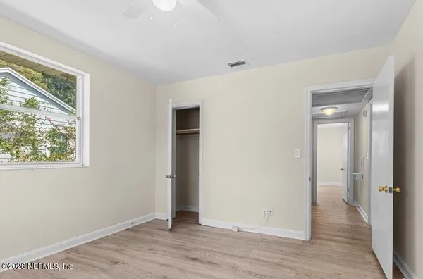 a view of an empty room with wooden floor and a window