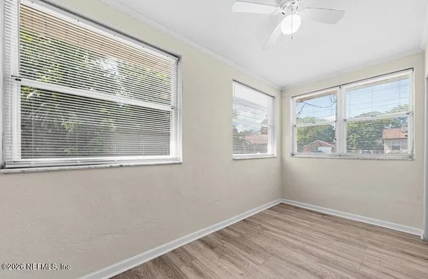 a view of an empty room with wooden floor and a window