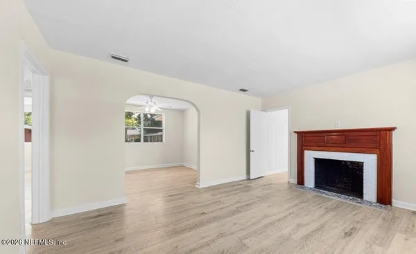 an empty room with wooden floor fireplace and windows