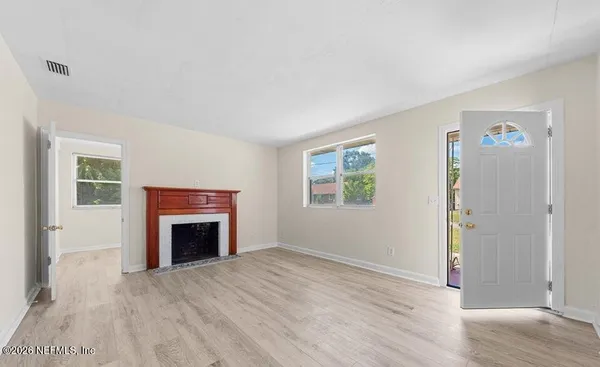 an empty room with windows and fireplace