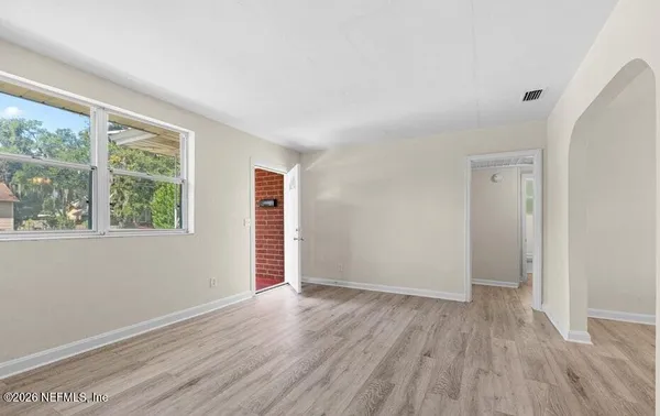 an empty room with wooden floor and windows