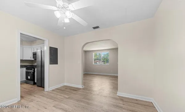 a view of an empty room with window and wooden floor