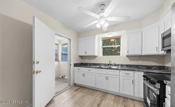 a kitchen with stainless steel appliances granite countertop a stove a sink and white cabinets