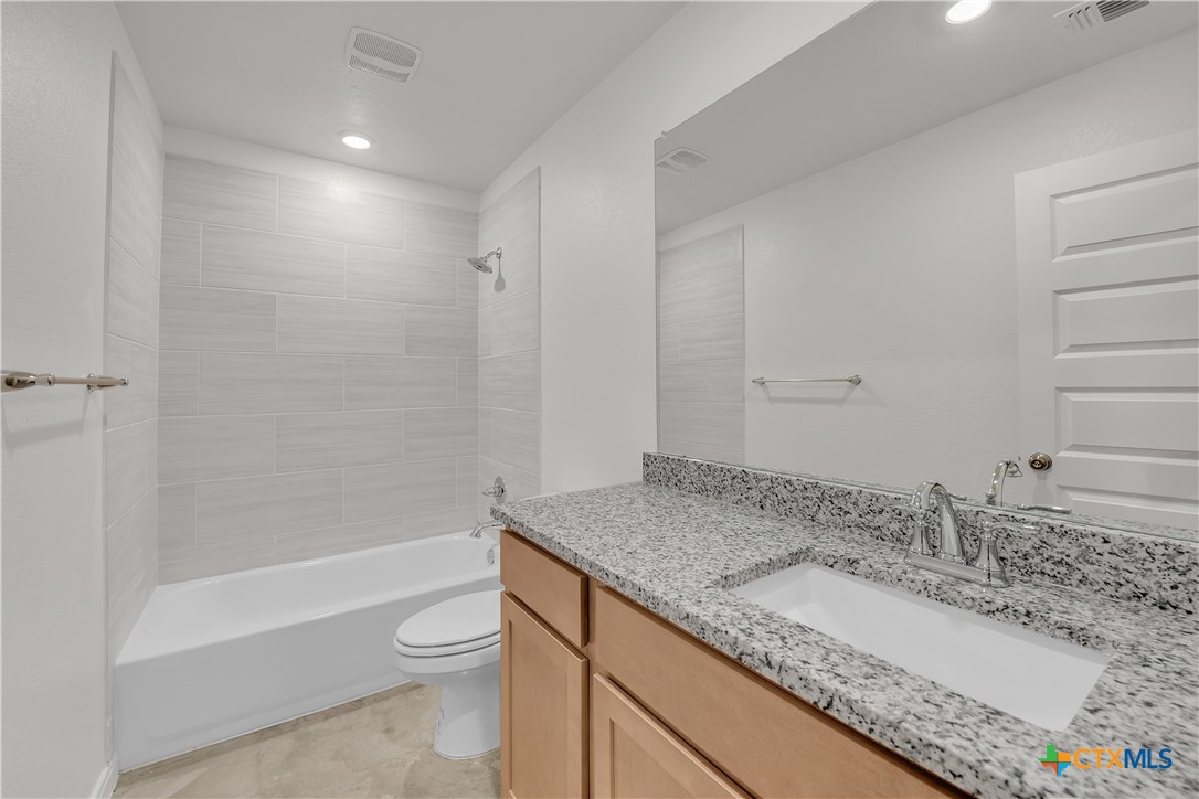 909 Wax Myrtle Court, Unit B Killeen, TX 76543 - Photo 12 of 15 a bathroom with a granite countertop sink a toilet and bathtub