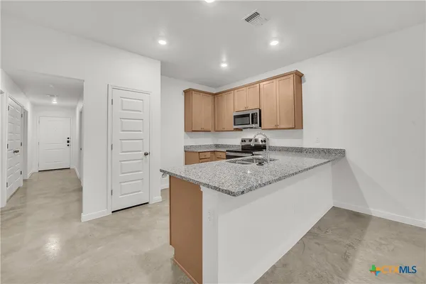 a kitchen with stainless steel appliances granite countertop a sink and a refrigerator
