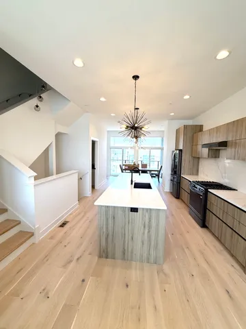 a large kitchen with stainless steel appliances kitchen island a large counter top and a wooden floors