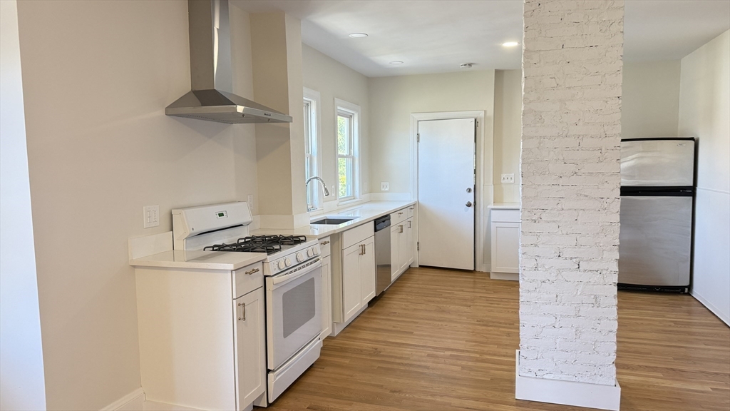 12 Eliot Street, Unit 12 Medford, MA 02155 - Photo 2 of 11 a kitchen with stainless steel appliances white cabinets and wooden floor