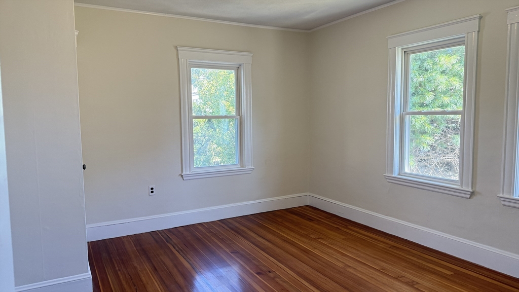 12 Eliot Street, Unit 12 Medford, MA 02155 - Photo 7 of 11 an empty room with wooden floor and windows